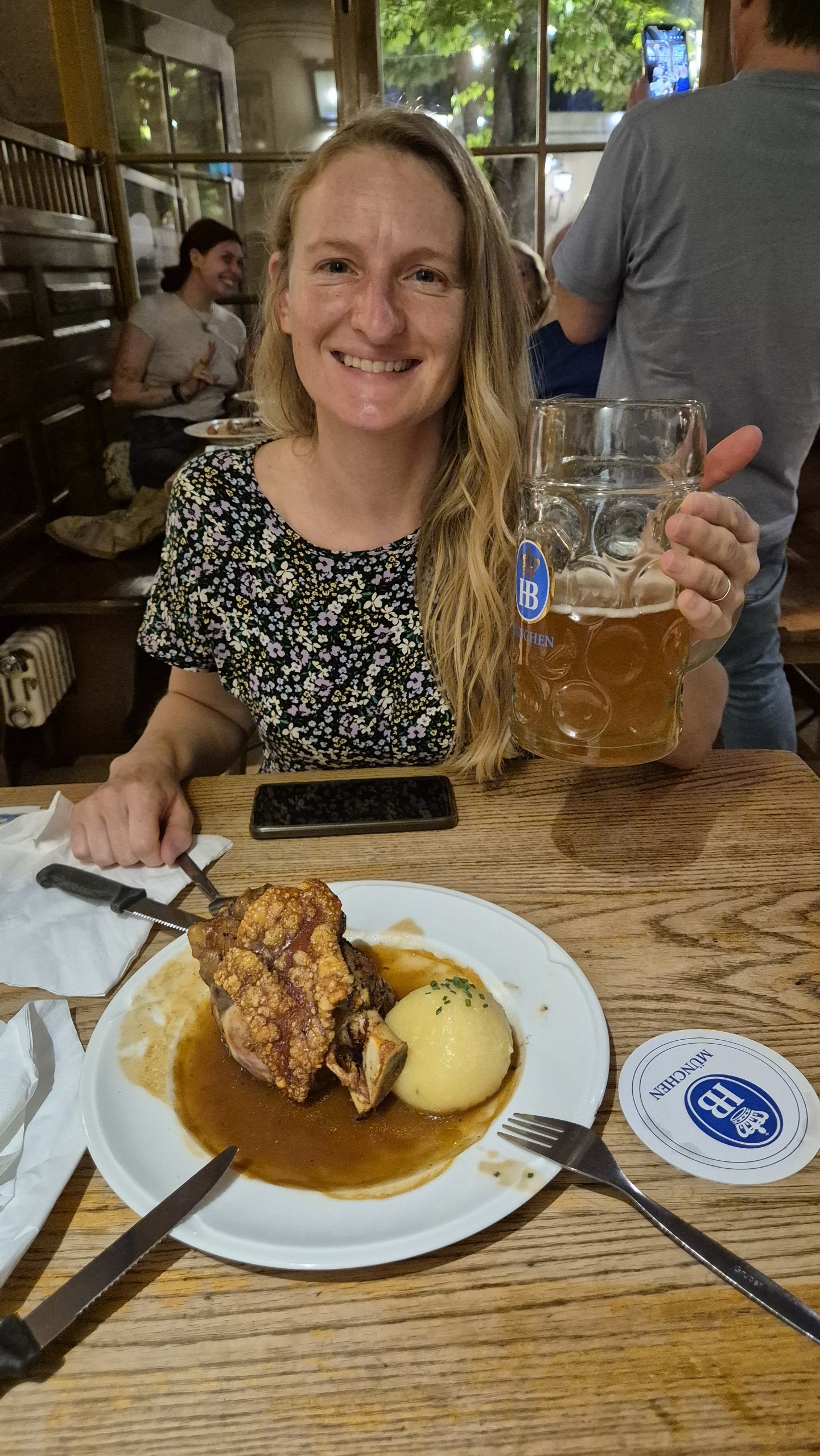 Caro with a beer stein and plate of Schweinshaxe at the Hofbrauhaus