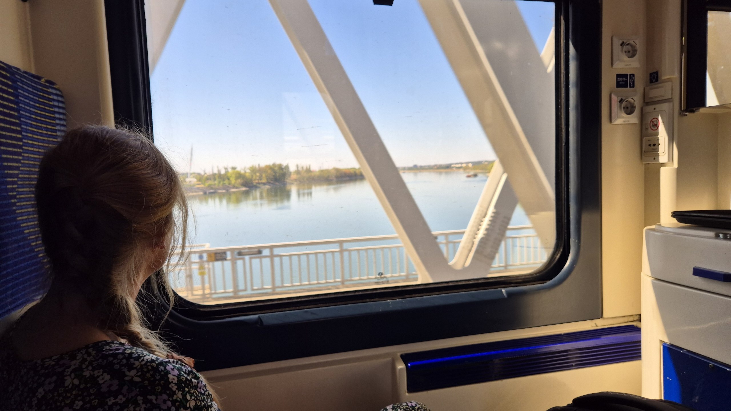 Caro looking through the train window while crossing the Danube in the morning