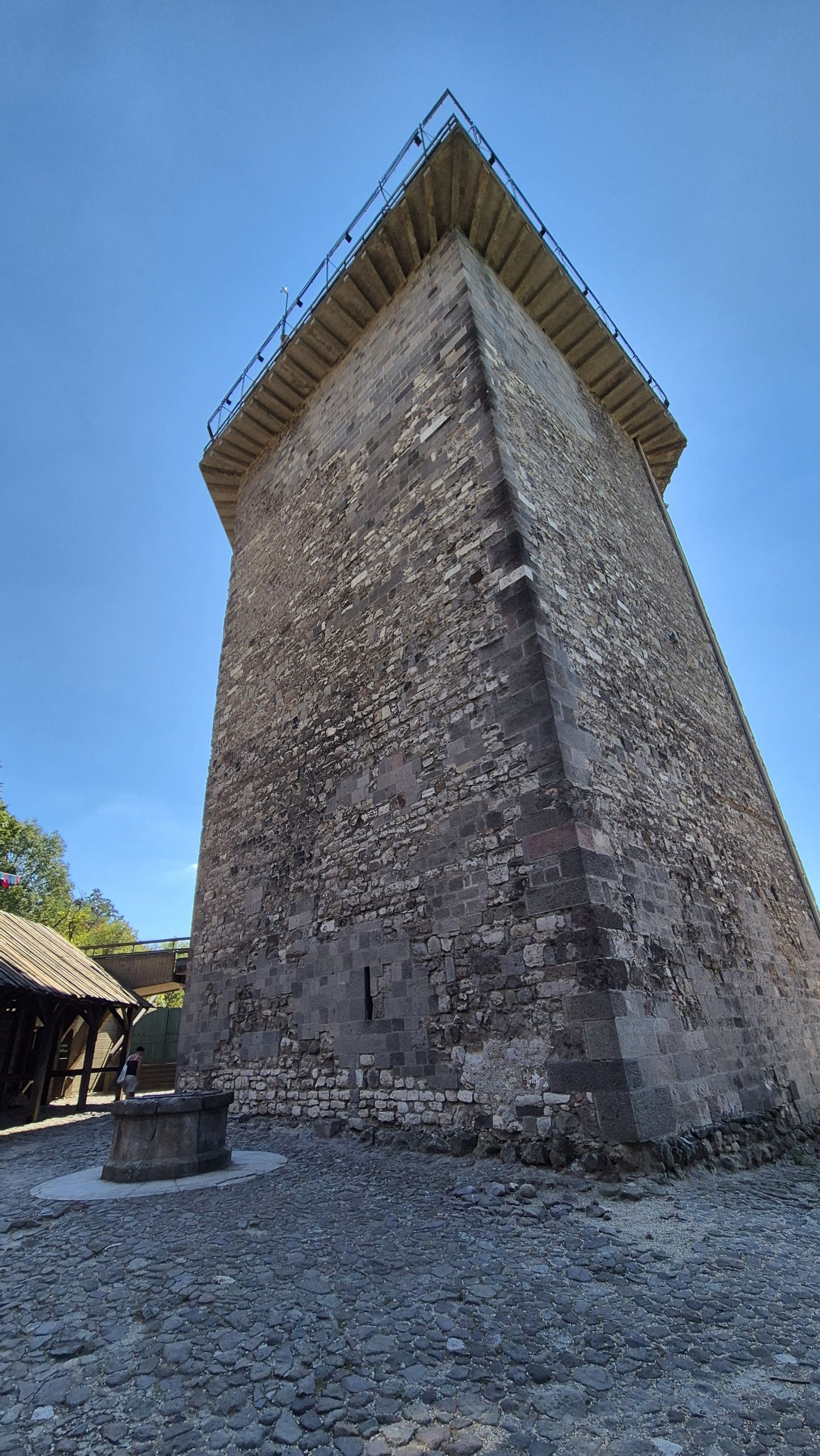 Looking up at the massive stone exterior of Solomon’s Tower beneath a clear blue sky