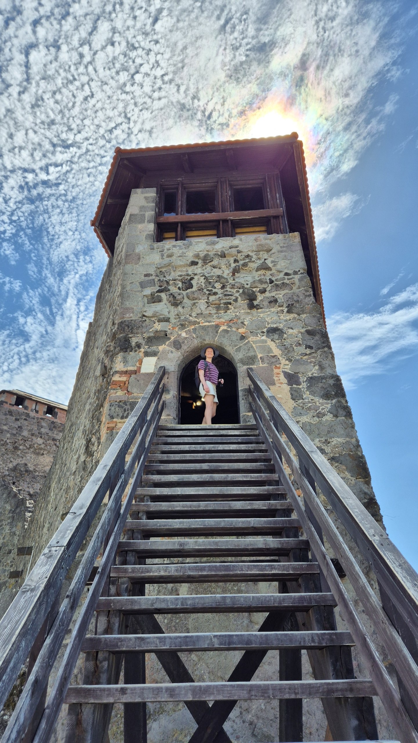 Caro climbing the wooden stairs of a stone tower in Visegrád Citadel