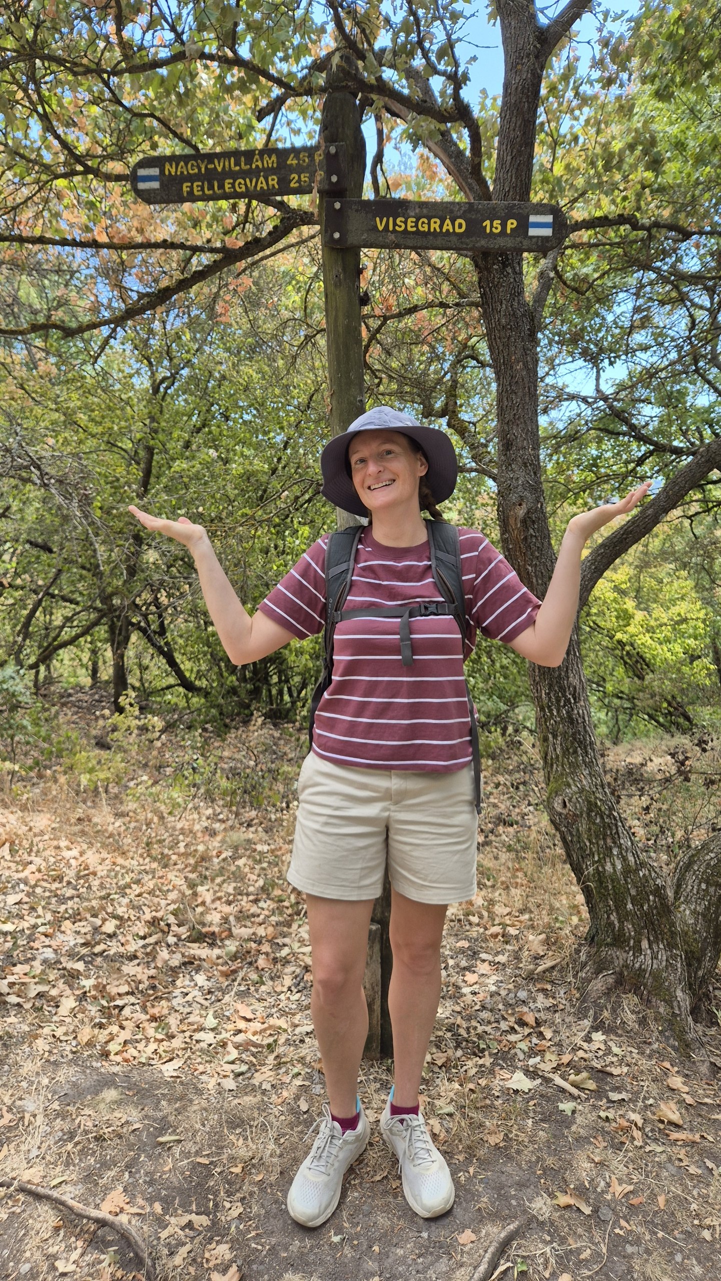 Caro standing beneath hiking signs in the wooded hills above Visegrád