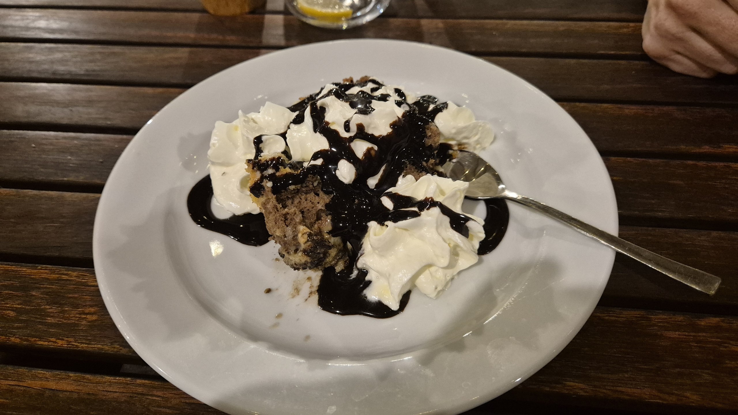 A plate of Somlói galuska with chocolate sauce and whipped cream