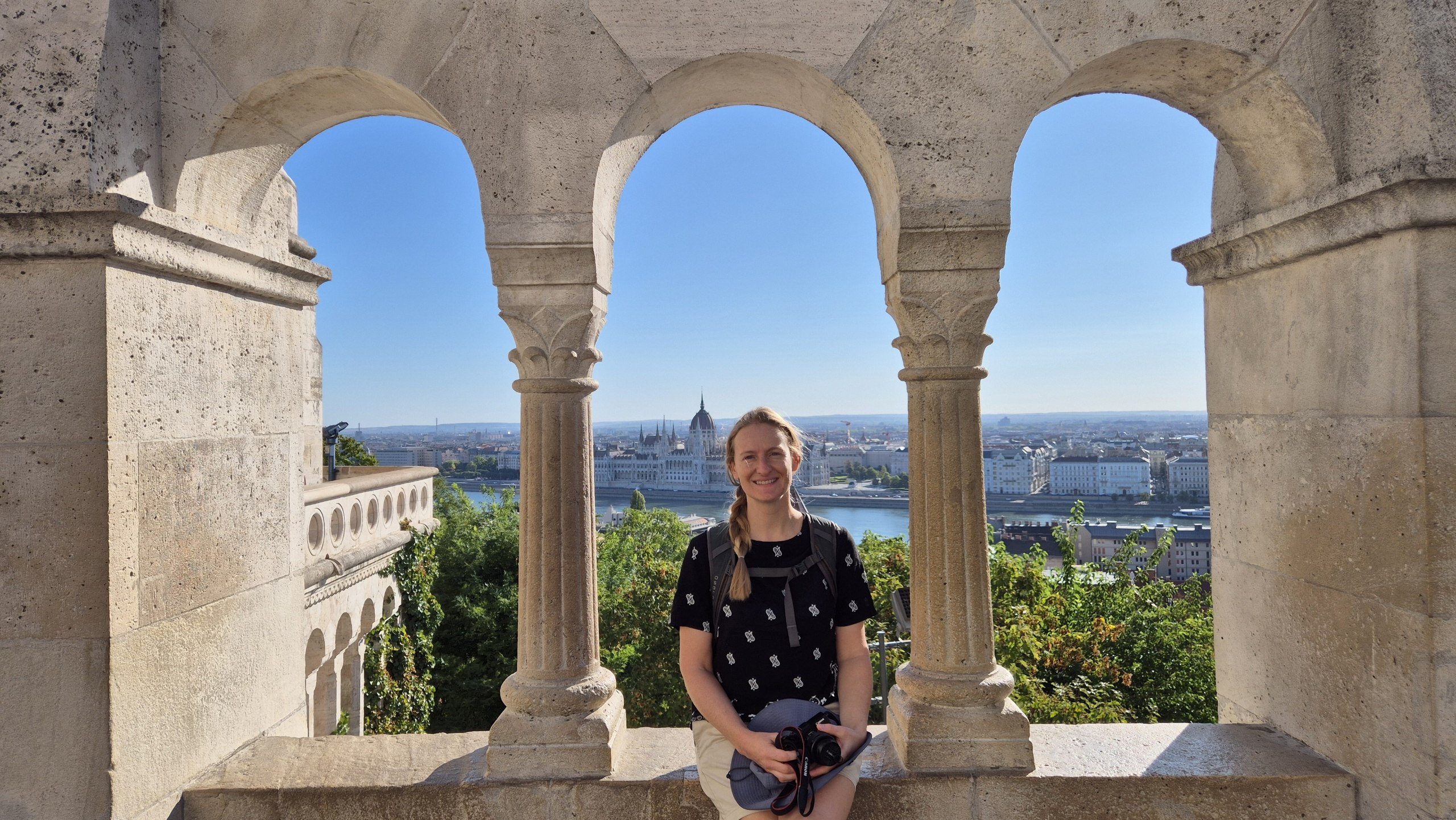 Caro framed by the arches of Fisherman's Bastion with the Hungarian Parliament behind her