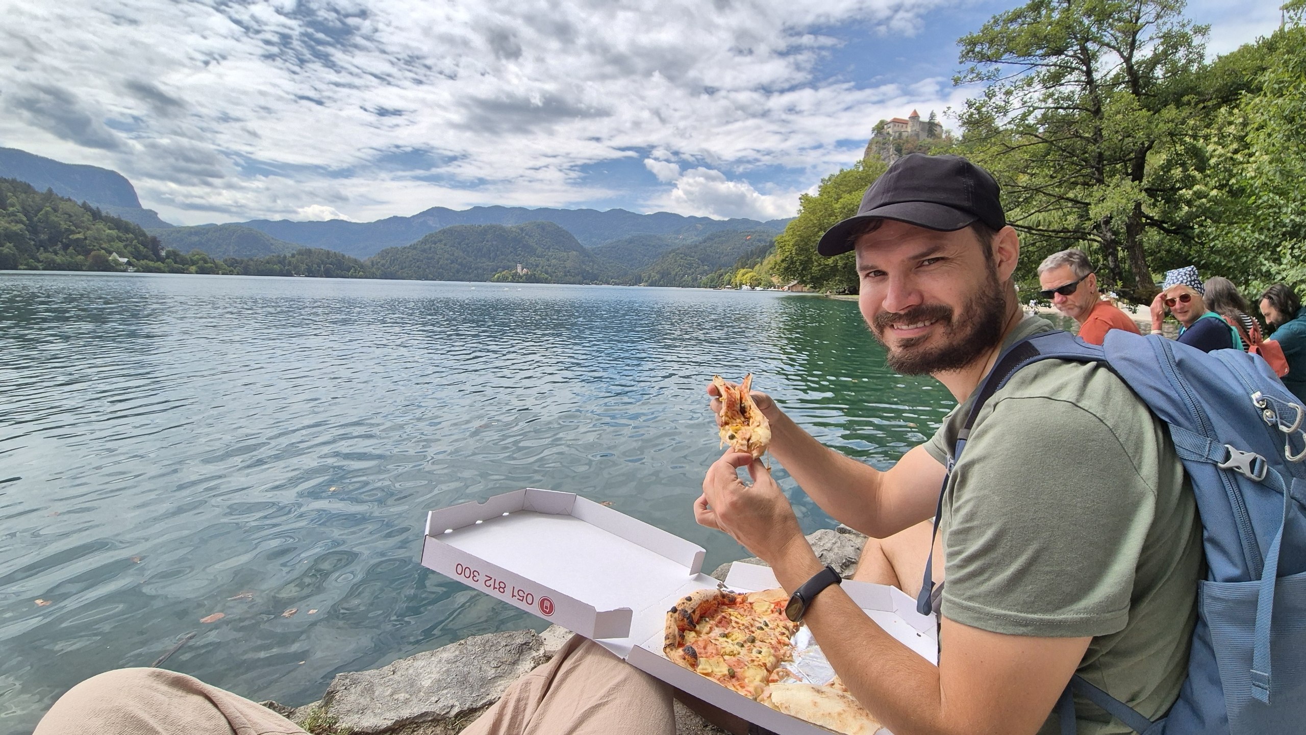 Hugo eating takeaway pizza beside Lake Bled