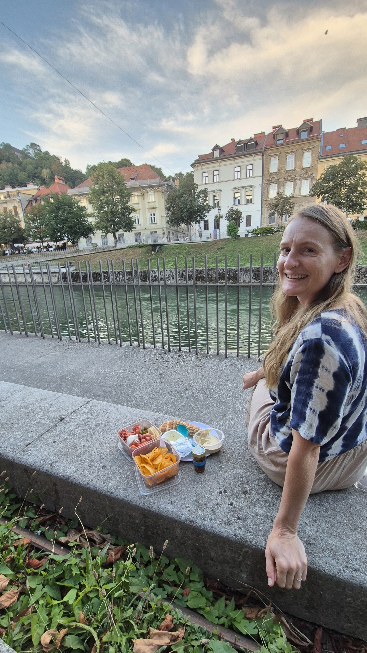 Caro eating a picnic dinner beside the Ljubljanica River