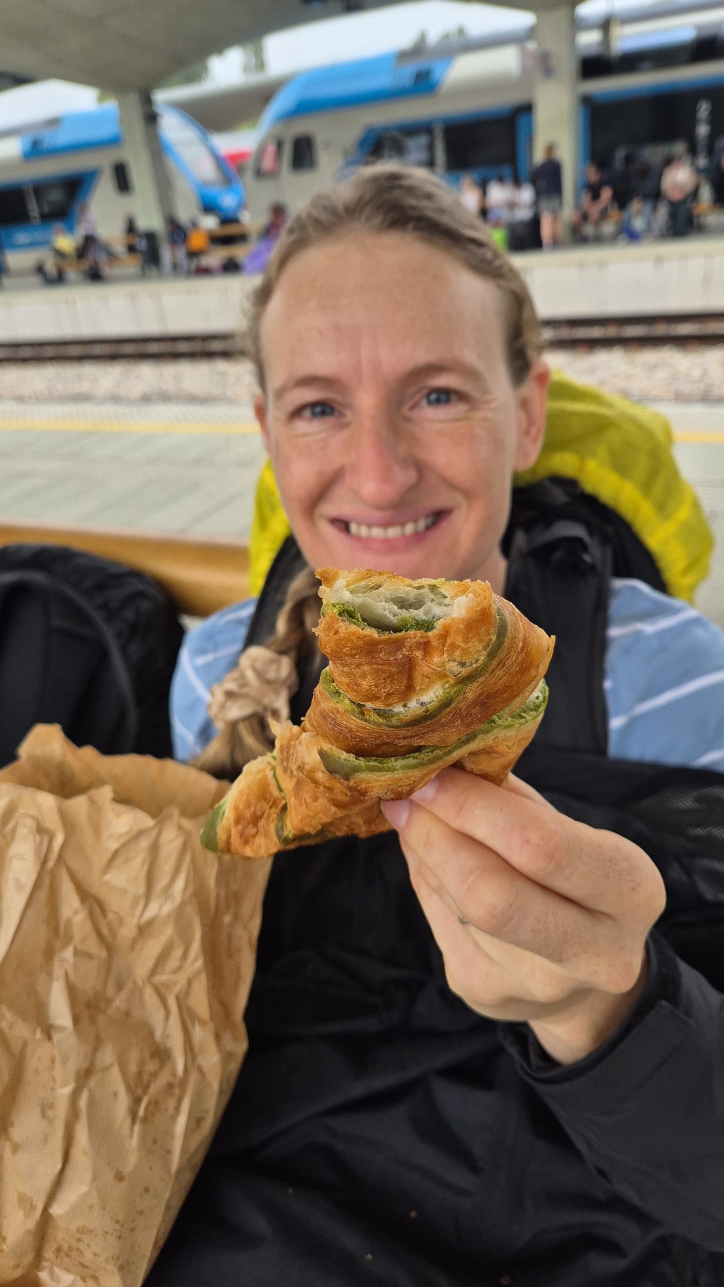 Caro holding a pistachio croissant while waiting for the bus in Ljubljana