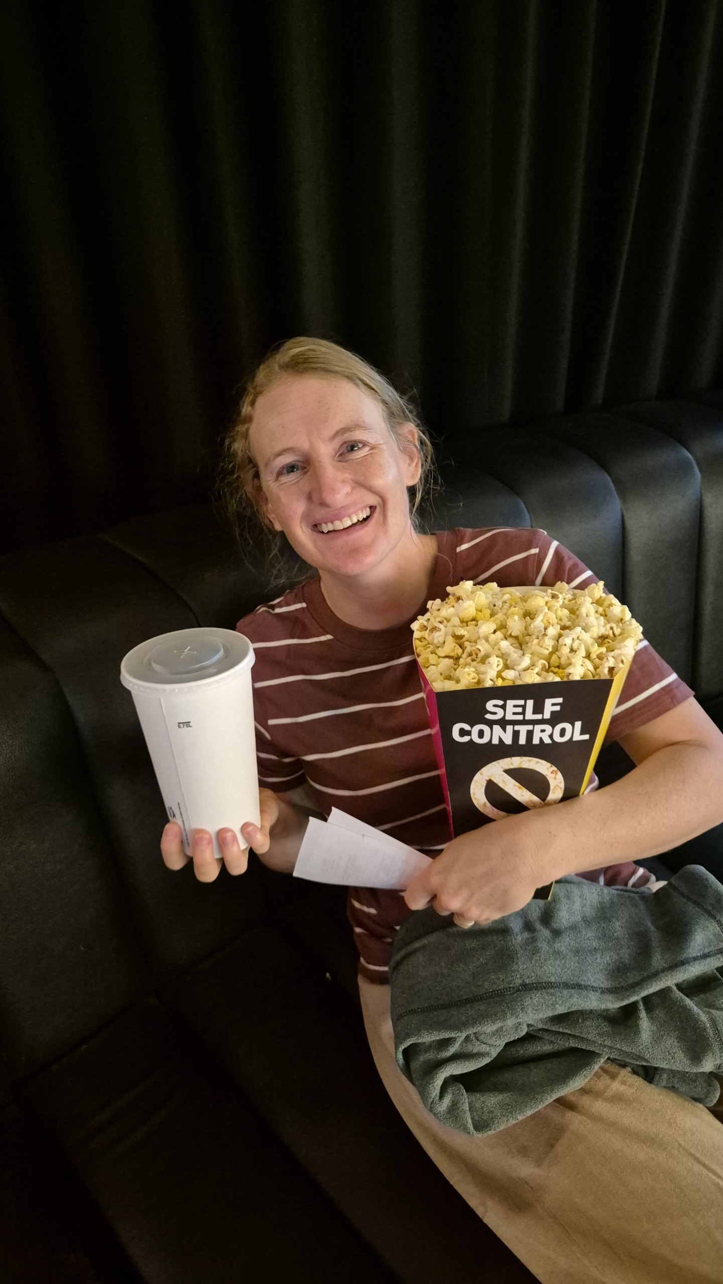 Caro holding an enormous box of popcorn and a drink at Kaptol Boutique Cinema