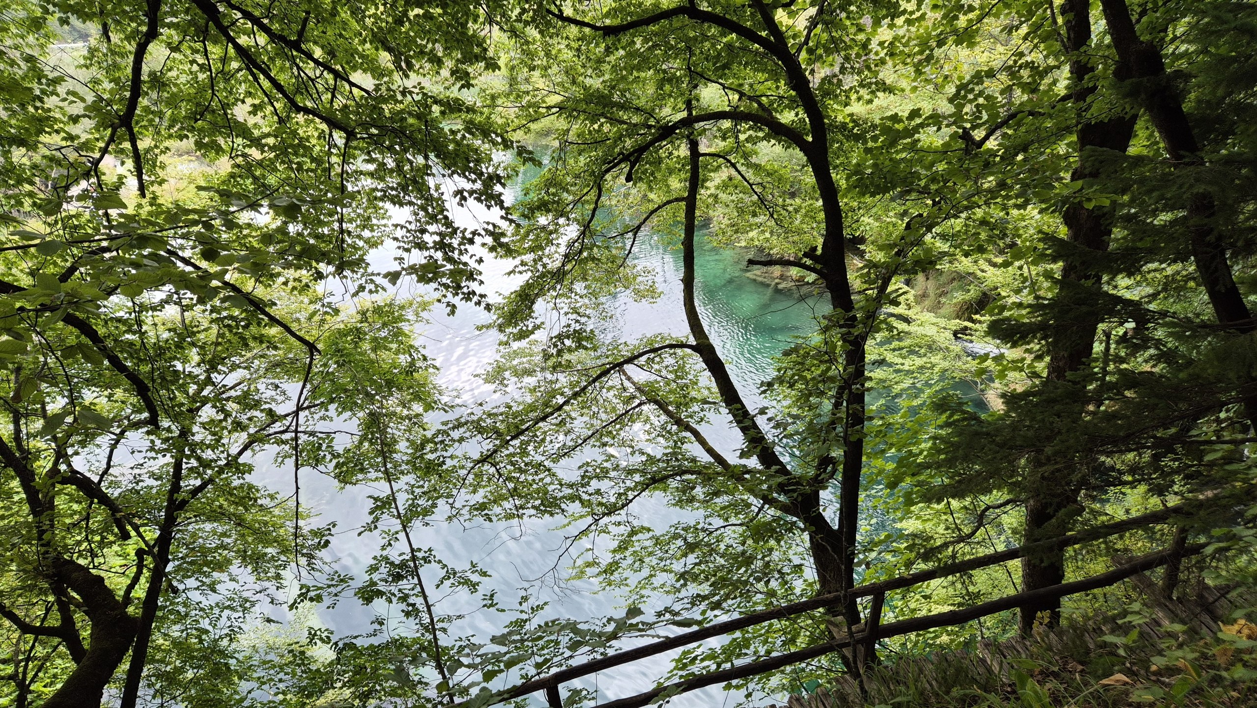A wooden boardwalk following a bright blue Plitvice lake