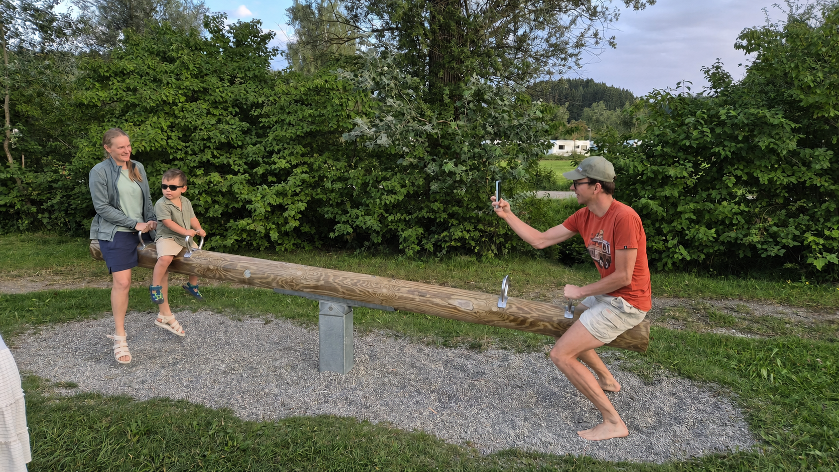 The Kraemers playing on a wooden seesaw, with sunglasses covering the child’s eyes