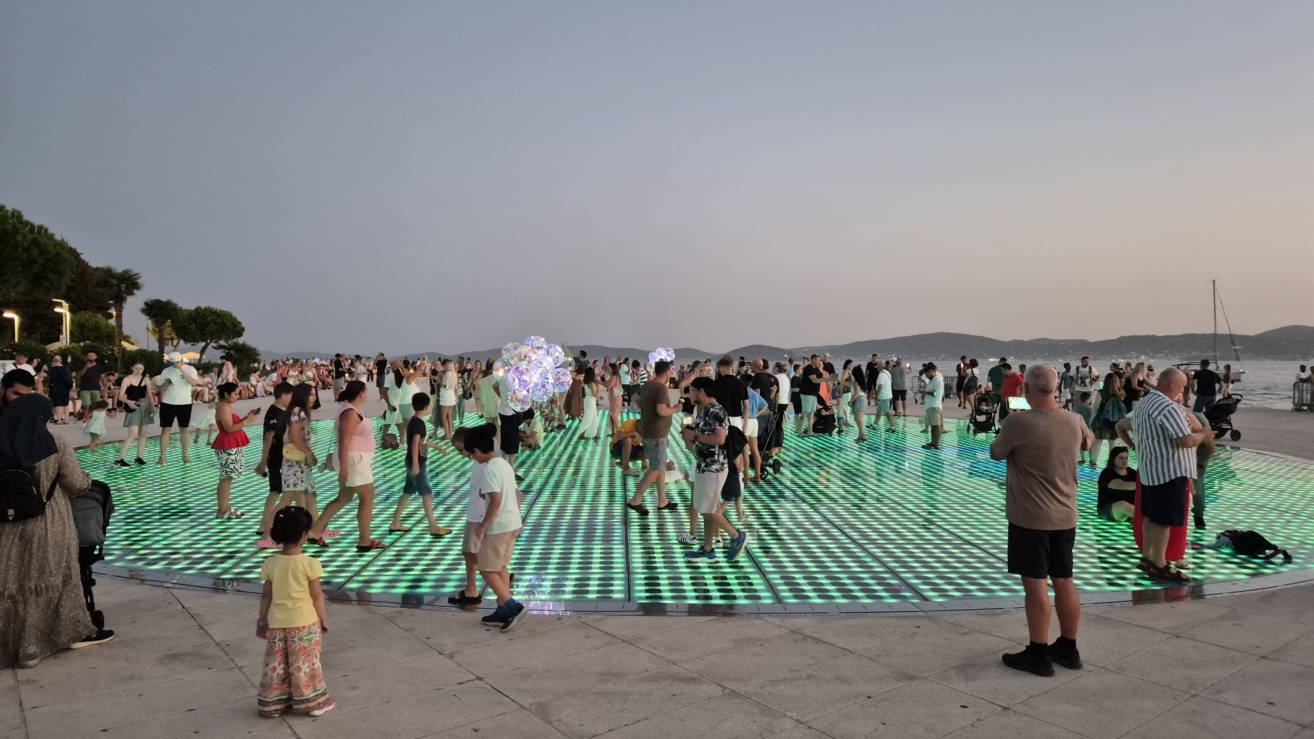 Visitors standing on the illuminated Greeting to the Sun installation in Zadar