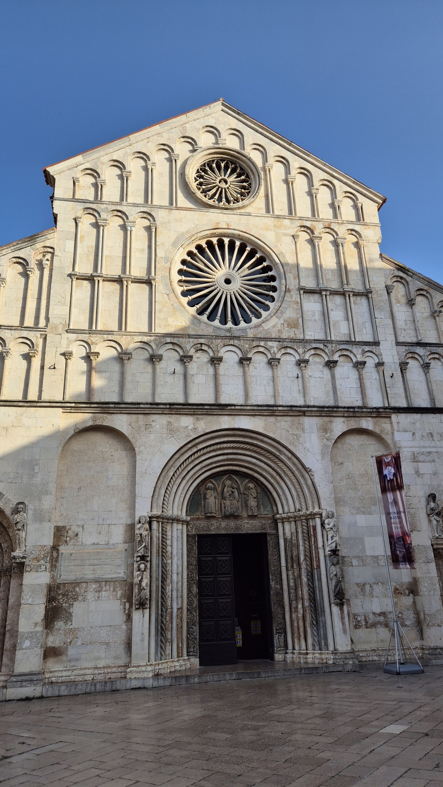 The pale stone facade of Zadar Cathedral under a clear blue sky