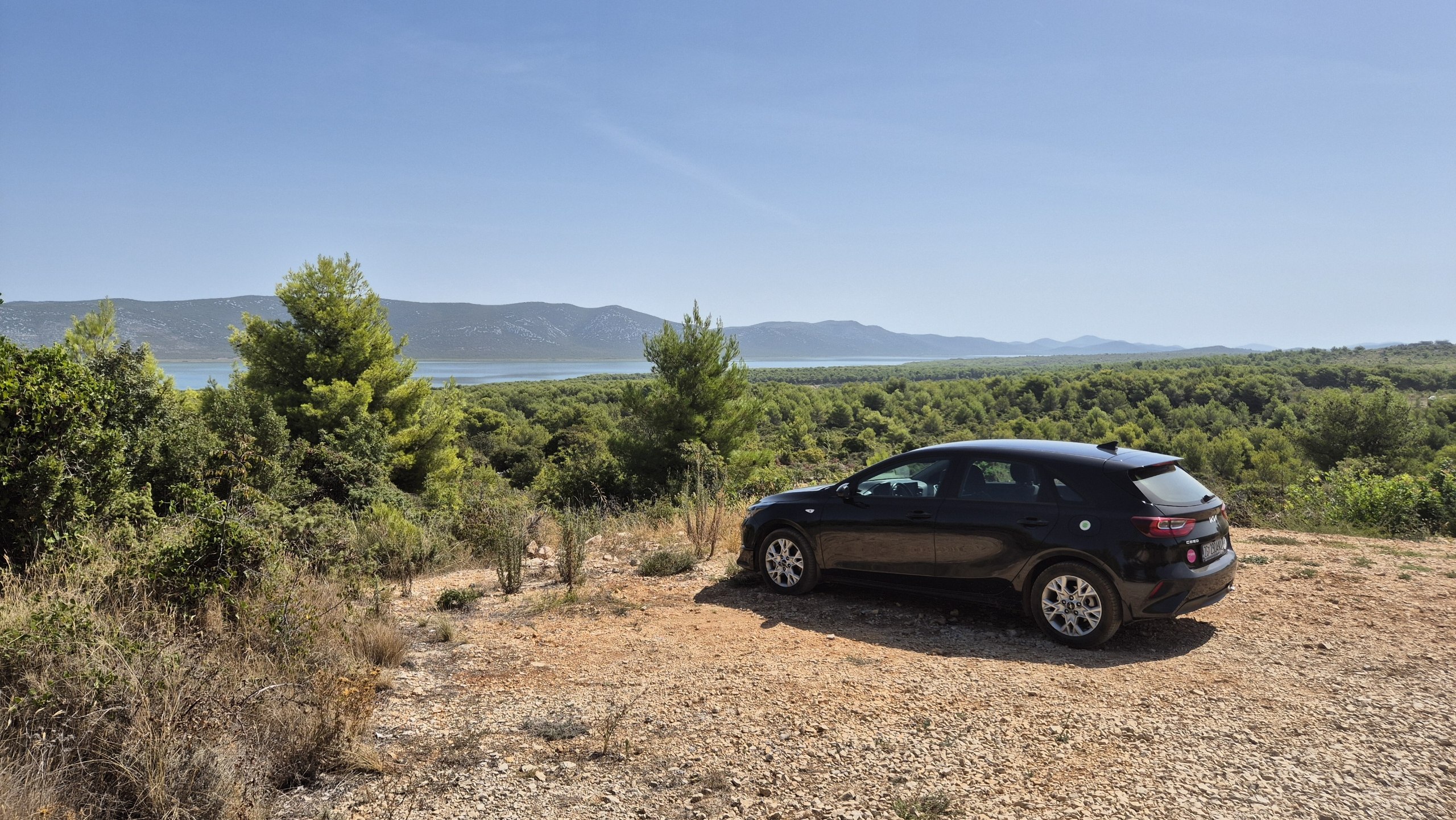 The rental car parked below a hot coastal viewpoint
