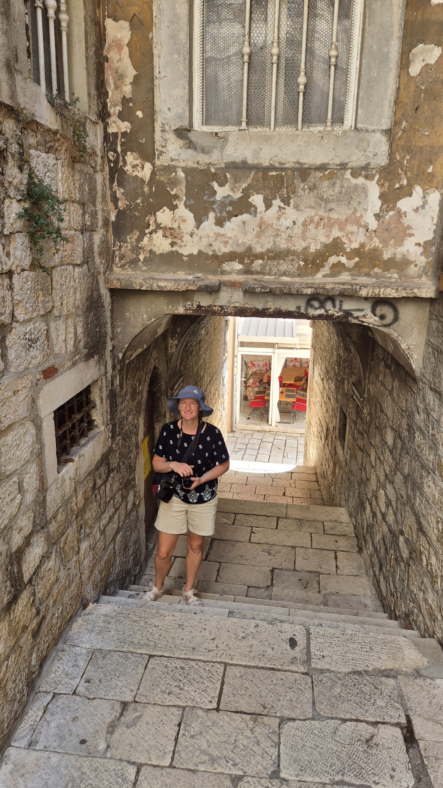 Caro climbing a narrow flight of stone steps in Šibenik old town