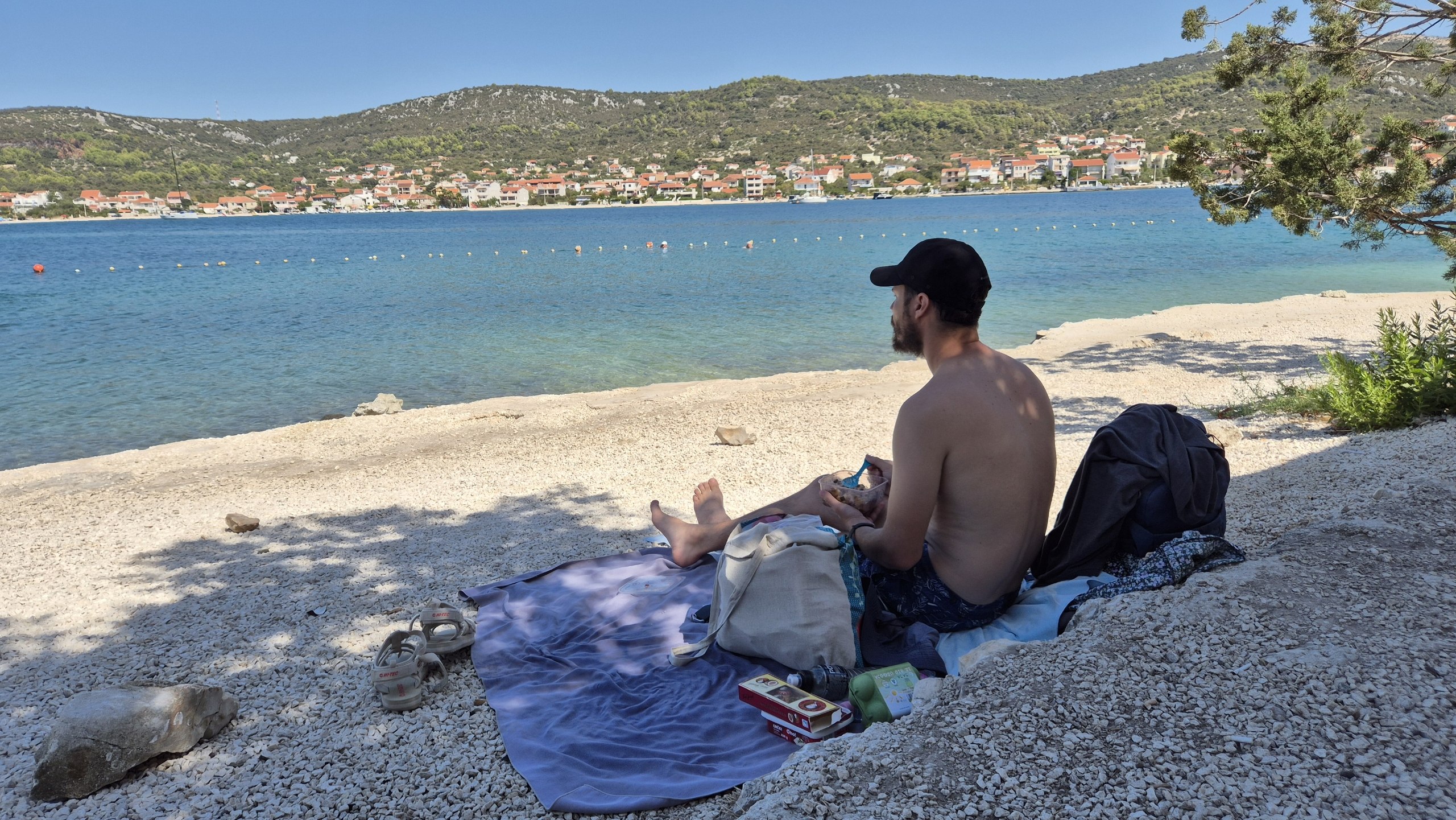 Hugo sitting in the shade beside the water at Plaža Smokvina