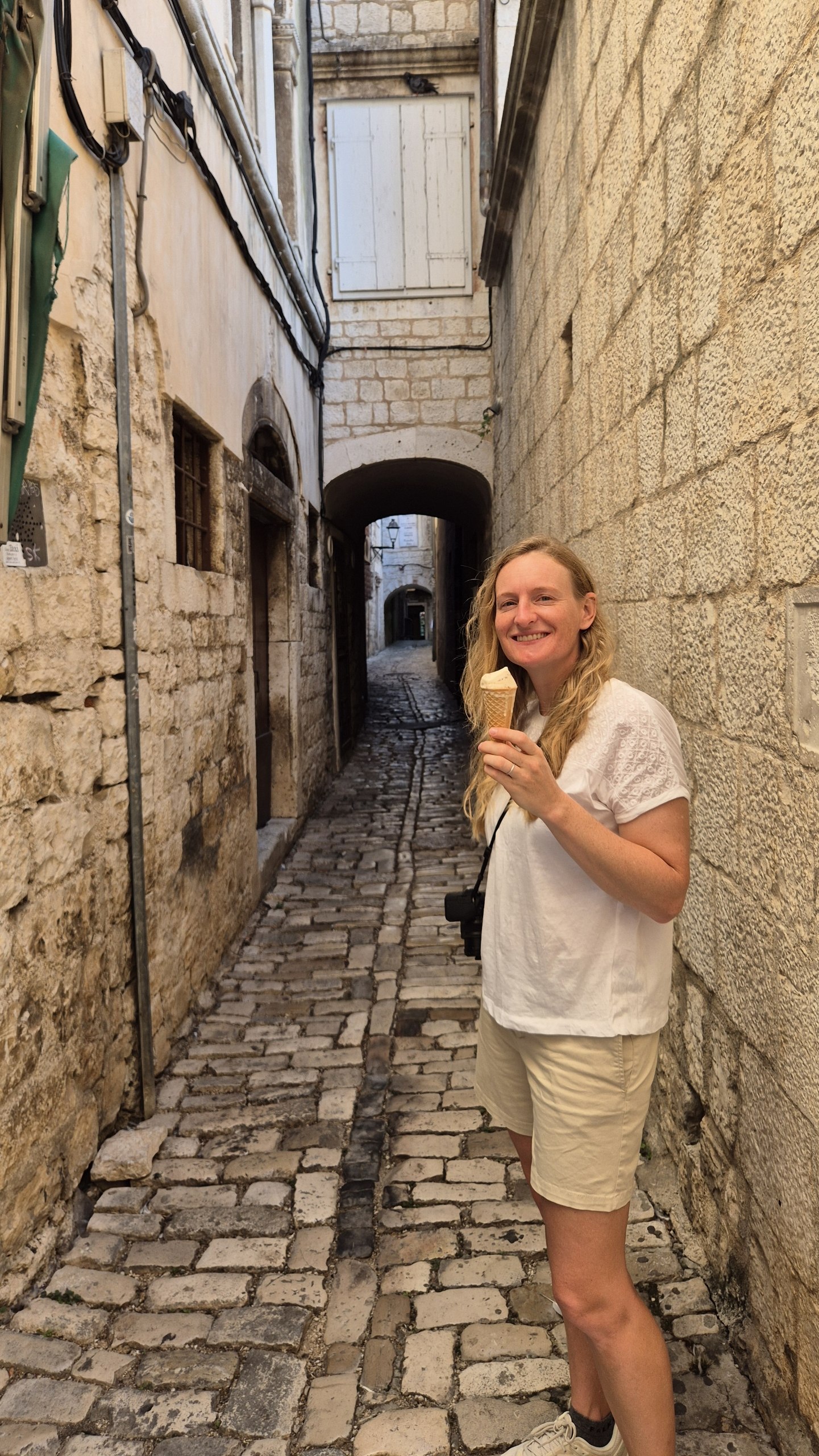 Caro eating an ice cream in one of Trogir's narrow stone lanes
