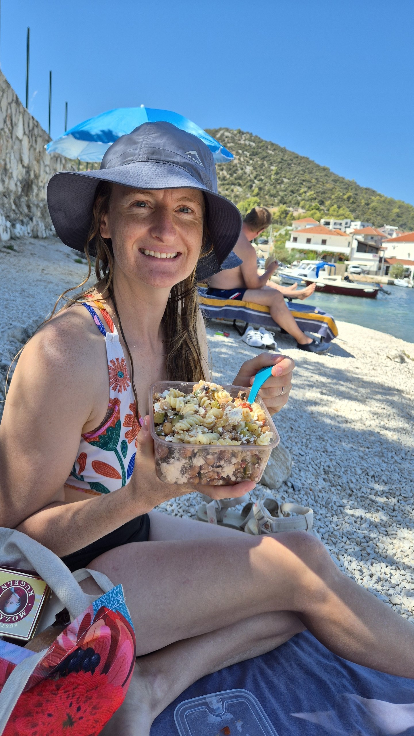 Caro eating leftover pasta for lunch on the beach