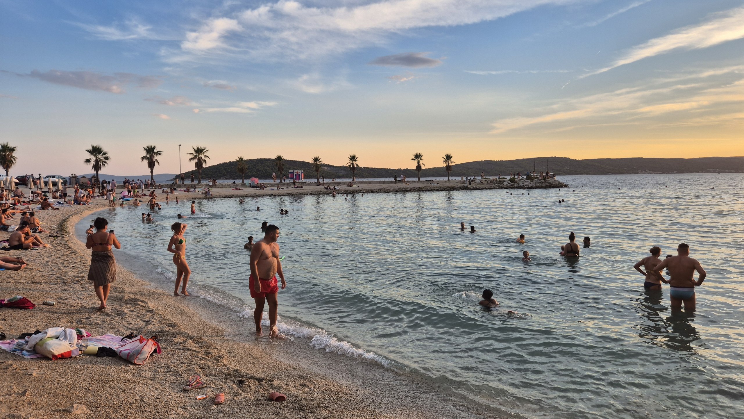 People swimming at Kašjuni Beach in the late afternoon