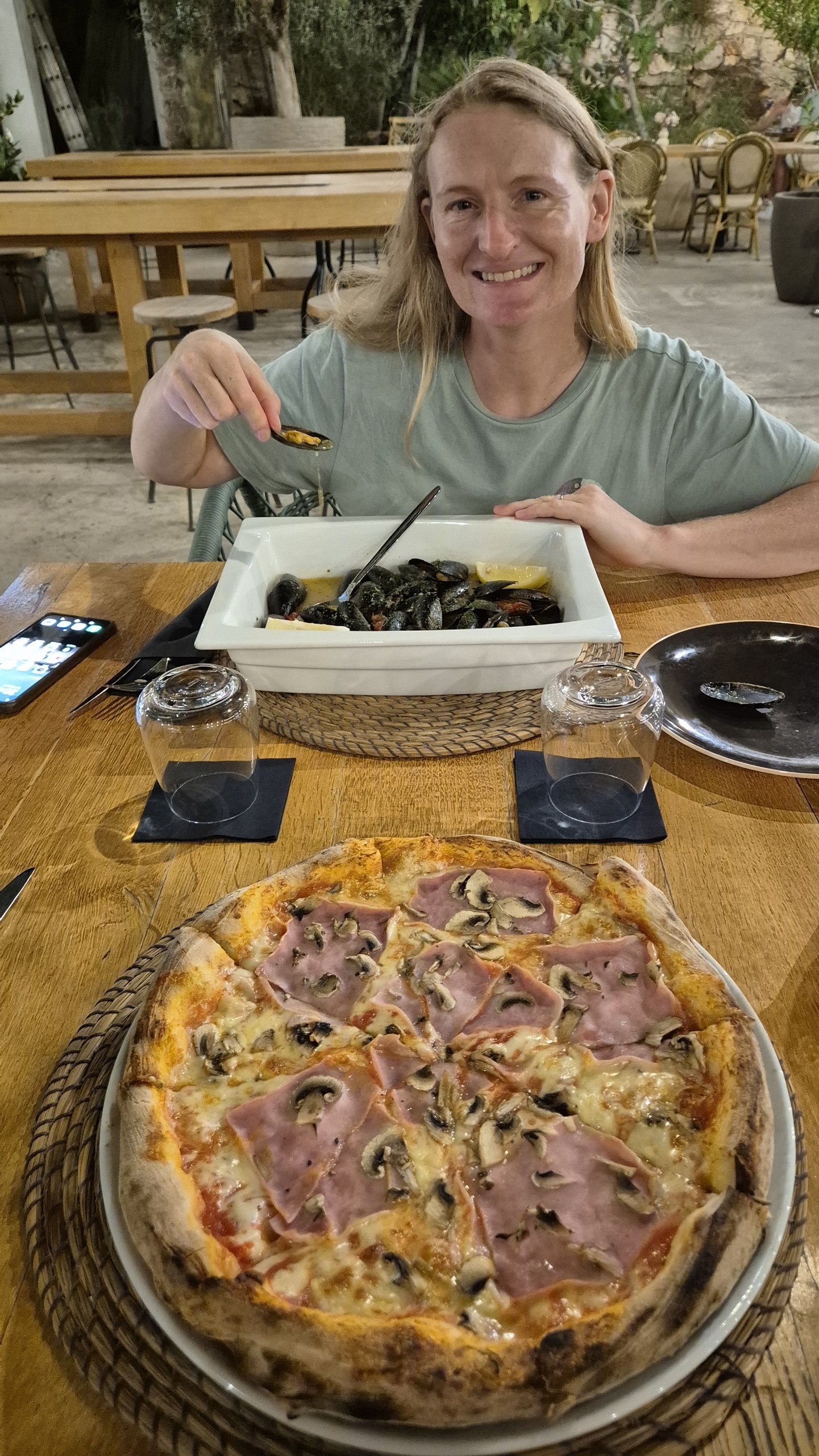 Caro with a bowl of mussels and a pizza at a restaurant in Stari Grad