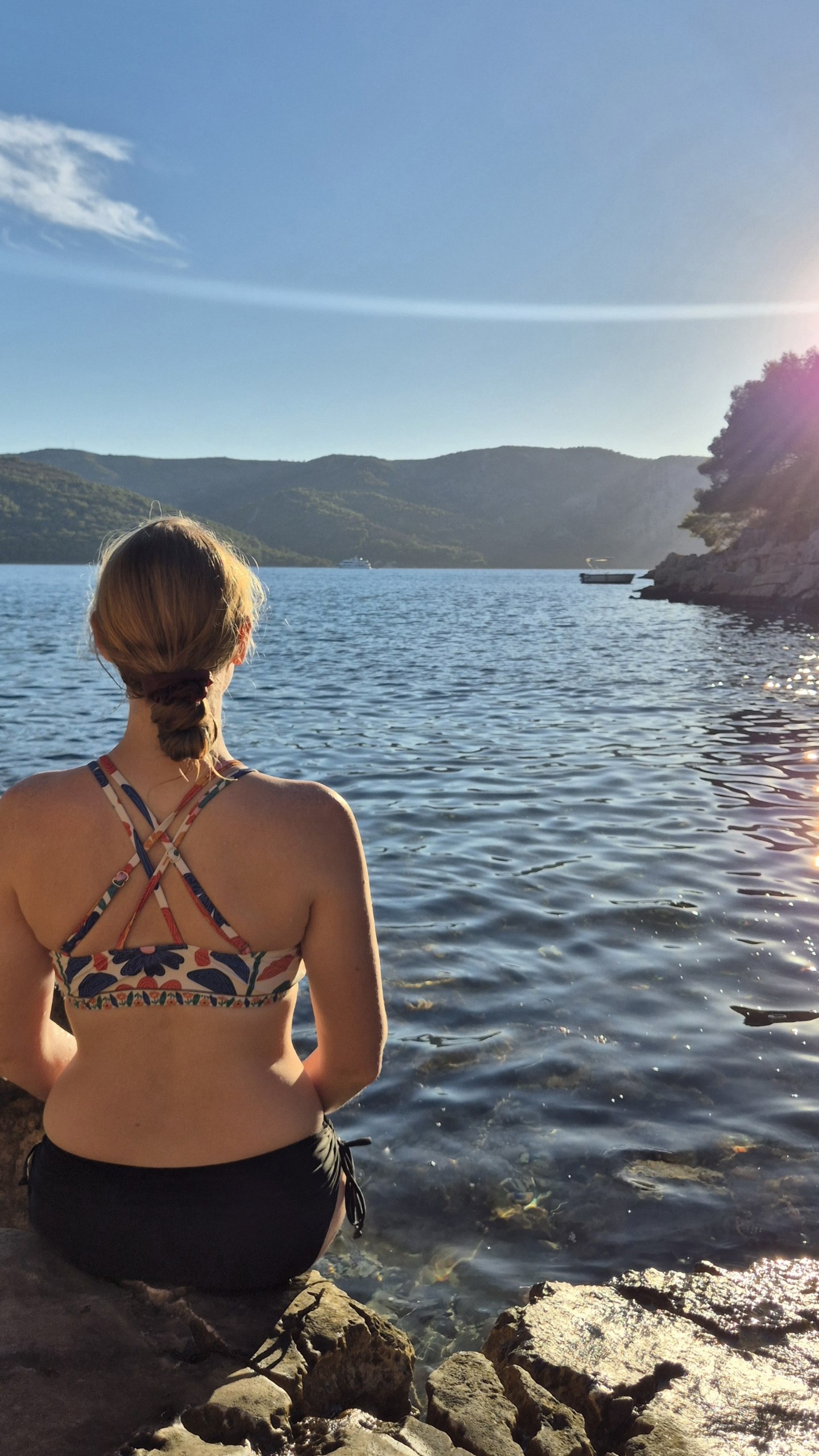 Caro sitting on the rocks beside Uvala Zavala in the late-afternoon light
