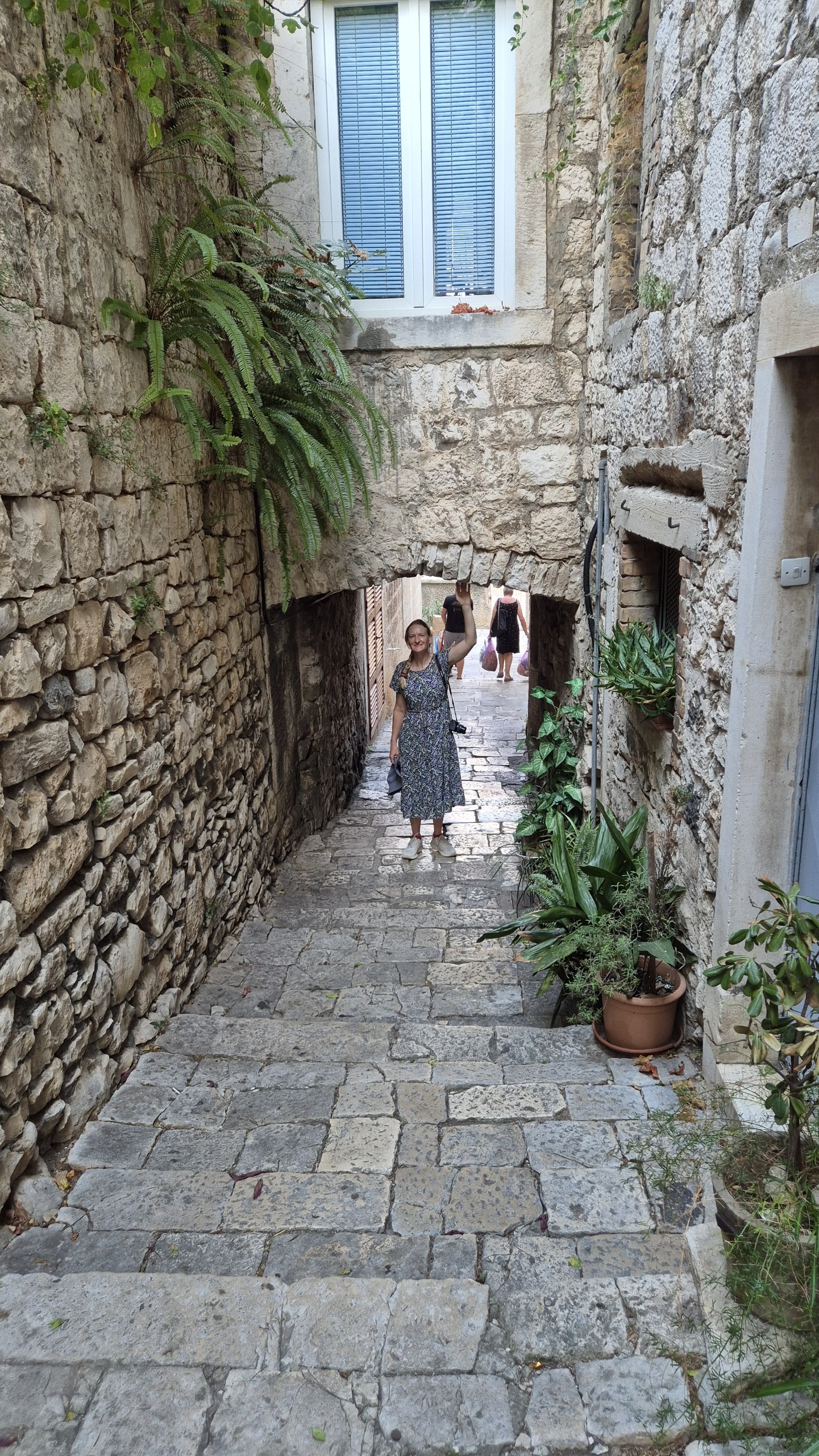 Caro standing beneath a low stone arch in a stepped Korcula alley