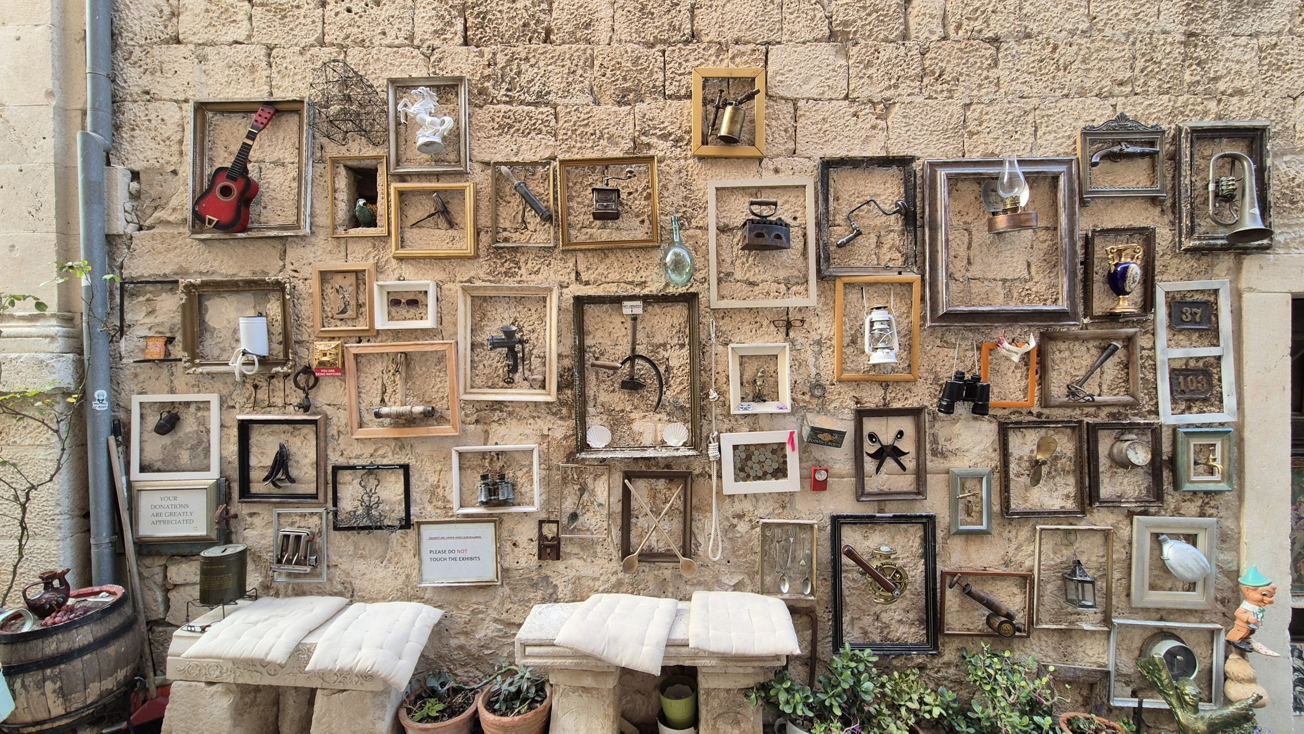 A playful outdoor wall display of framed found objects in Korcula
