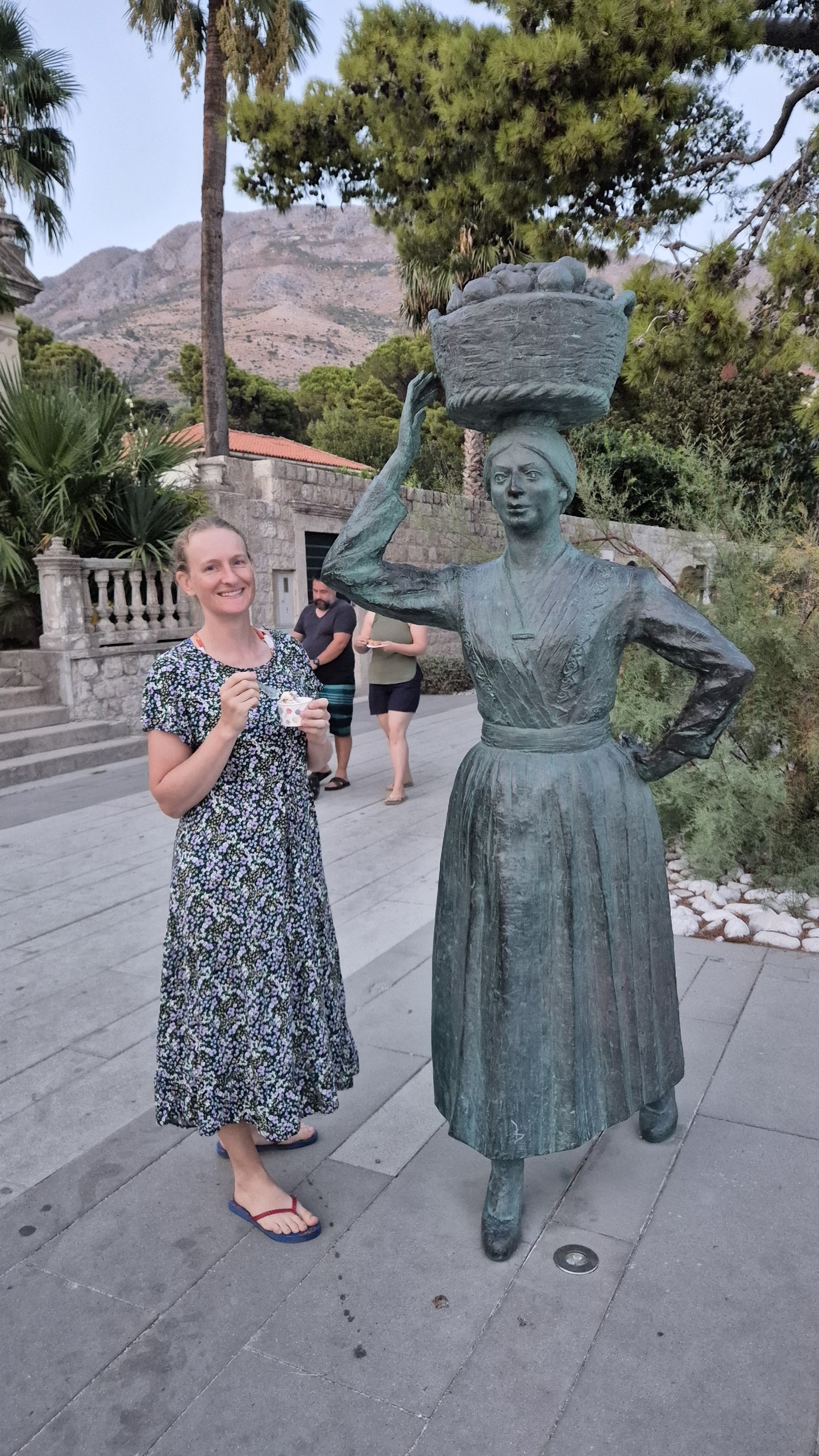 Caro eating Ferrero Rocher ice cream beside a statue of a market woman