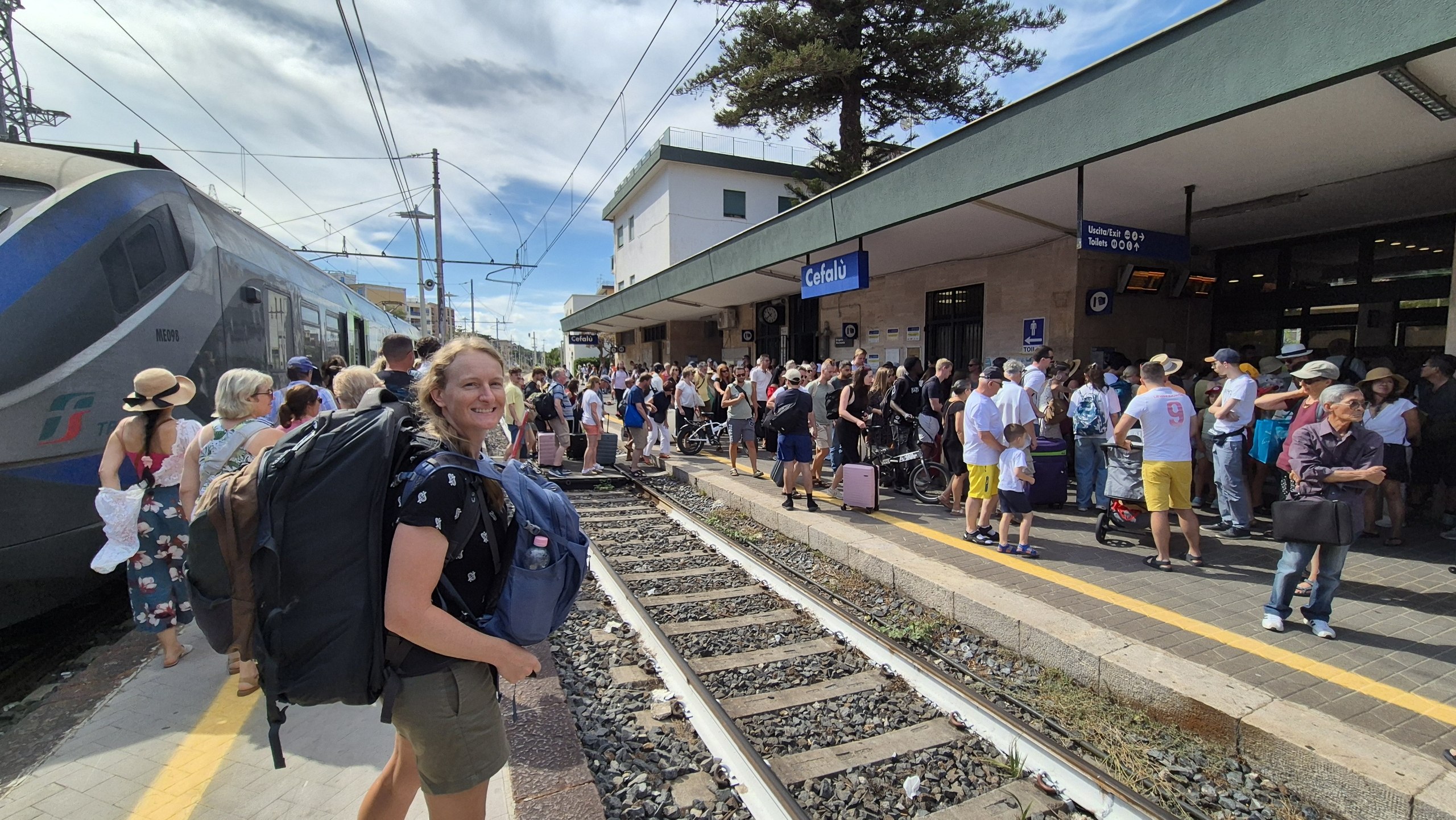 day52-cefalu-station-crowd Caro with both backpacks among the crowd on the platform at Cefalù station