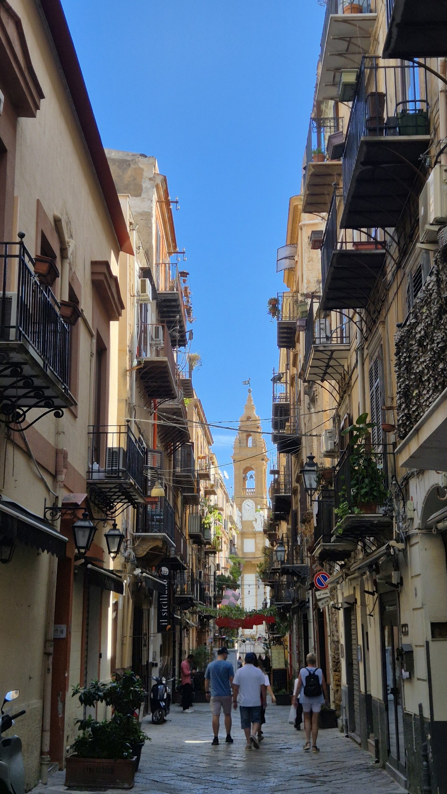 day52-palermo-street-to-station A narrow Palermo street with balconies and a church tower at the end