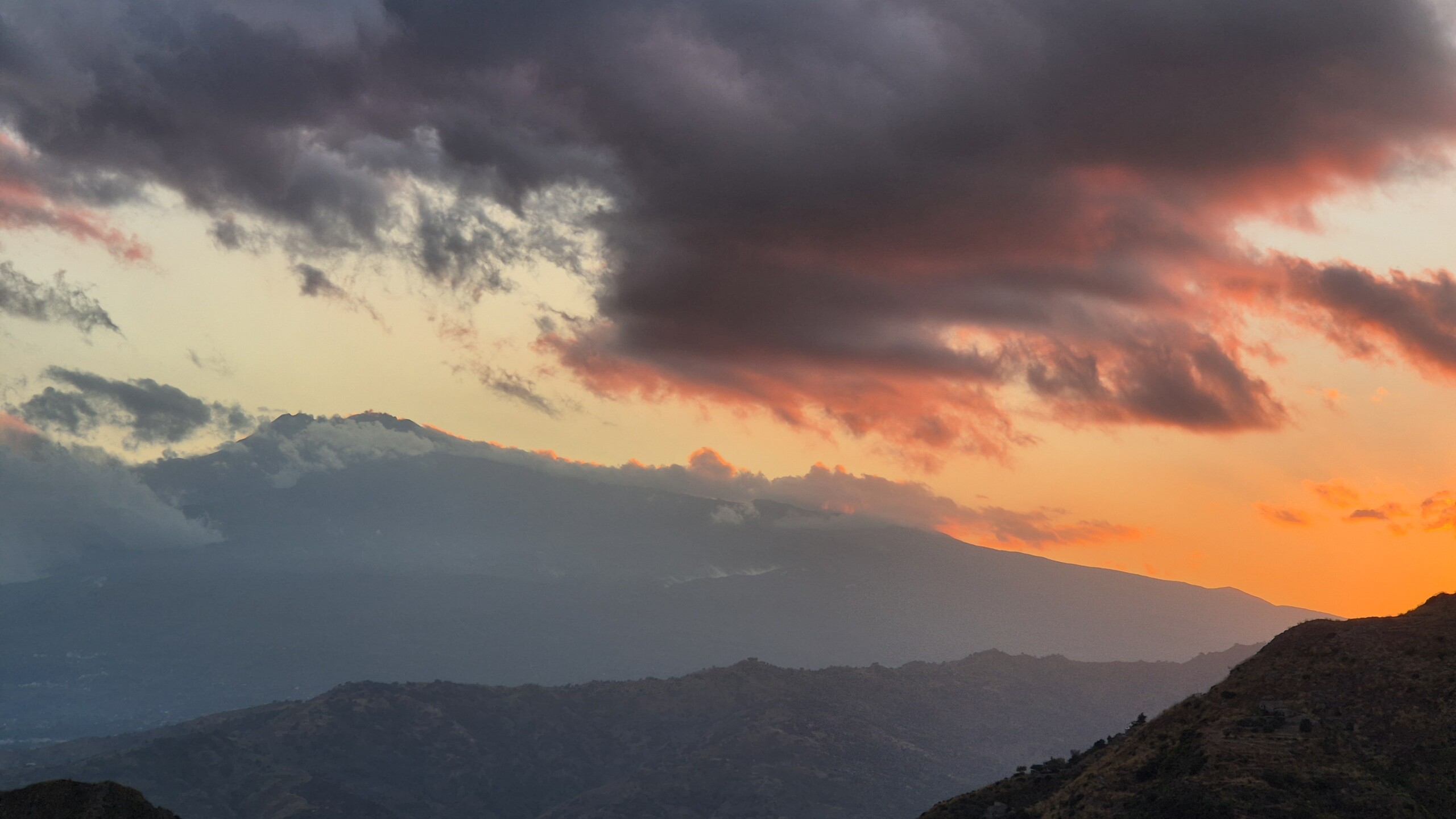 The peak of Mount Etna finally clear of cloud at sunset, seen from Castelmola
