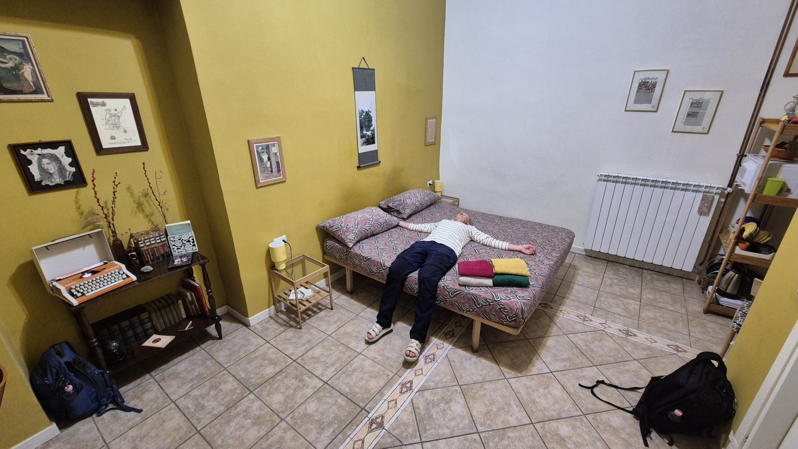 day60-collapsed-naples-room Caro face down on the bed in the Naples room, bags dropped where they landed