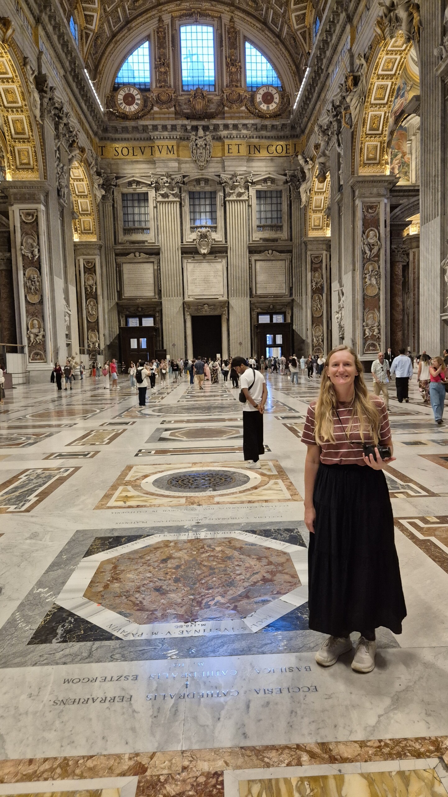 day64-caro-st-peters-nave Caro standing on the marble floor of St Peter's among the markers naming other cathedrals