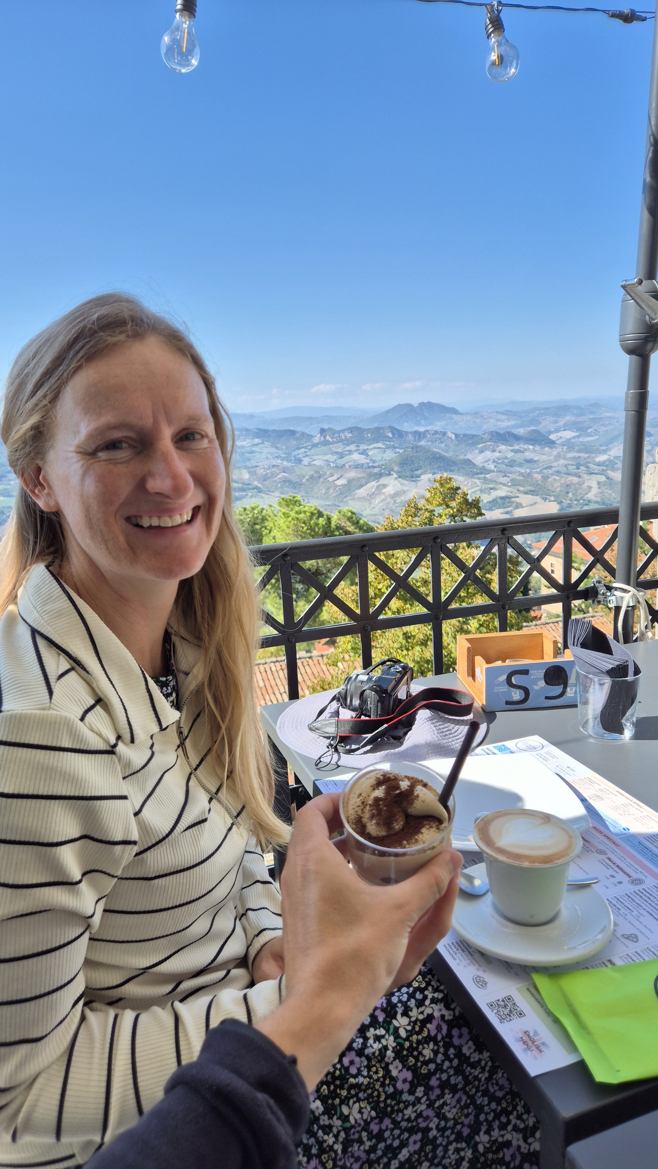 day69-san-marino-breakfast-view Caro with cappuccino and cremino at a restaurant overlooking Italy